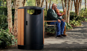 Grandfather and grandson sitting on a bench taking selfies together with wood and metal litter receptacle in foreground