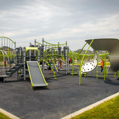 Green and grey playground on black PIP surfacing at Carrington Greenway Park in Calgary