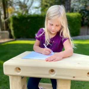 girl sitting in a wooden desk outdoors