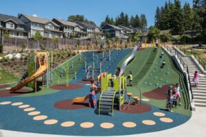 Queenston park in coquitlam featuring a playground at the bottom of a hill and slides and nets on the hillside