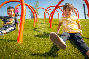 kids sliding down artificial turf for playgrounds
