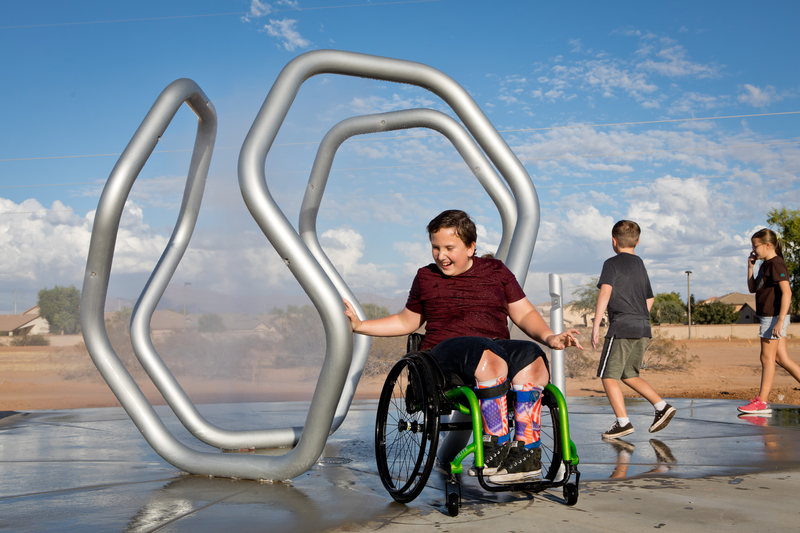 Boy in wheelchair getting misted in a waterpark