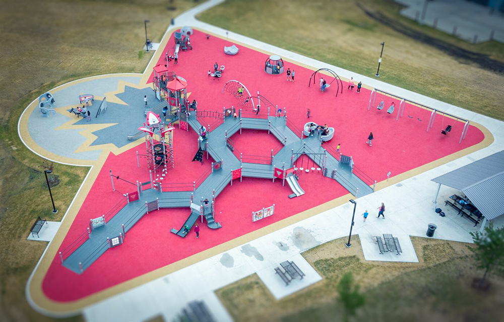 Aerial photo of jumpstart inclusive playground with ramps on red rubber surfacing with canadian tire logo