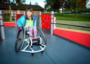 girl using wheelchair on playground ramp
