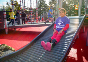 Girl going down roller slide on playground