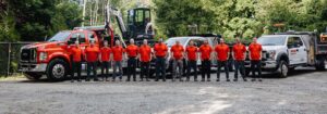 13 men in red shirts standing in front of Habitat trucks