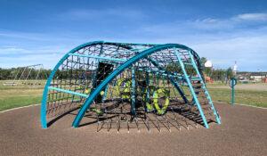 Blue and green playground with netting on PIP rubber surfacing