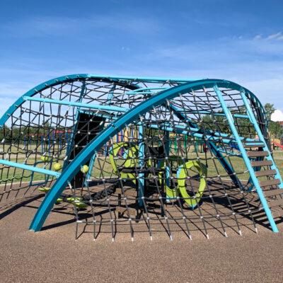 Blue and green playground with netting on PIP rubber surfacing