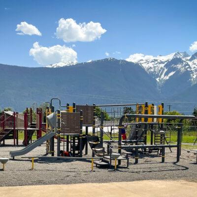 Grey and Yellow playground on gravel with mountains in background