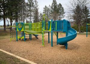 Green and blue playground and swings on wood fibre surfacing