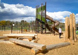 Green and brown playground tower with horizontal and vertical logs on wood fibre surfacing