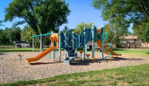 Blue and orange playground and swings on wood fibre