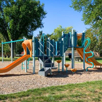 Blue and orange playground and swings on wood fibre