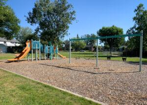 Blue and orange playground and swings on wood fibre