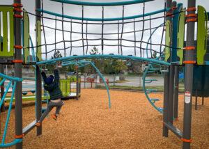 Child swinging under playground bridge