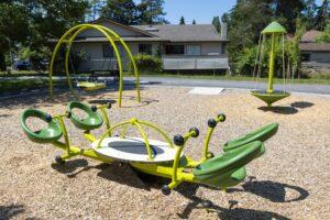 green seesaw and saucer swing on woodchips