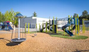 green, blue and silver playground on engineered wood fibre (EWF) & artificial grass surfacing