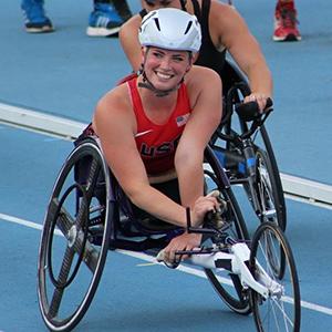 female wheelchair racer with short grey hair with helmet and racing attire