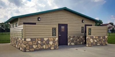 washroom building with Horizontal lap upper walls, flagstone lower walls with cedar shake roof and privacy screen