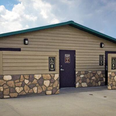 washroom building with Horizontal lap upper walls, flagstone lower walls with cedar shake roof and privacy screen