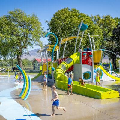 a group of kids playing in a water park with a big water slide