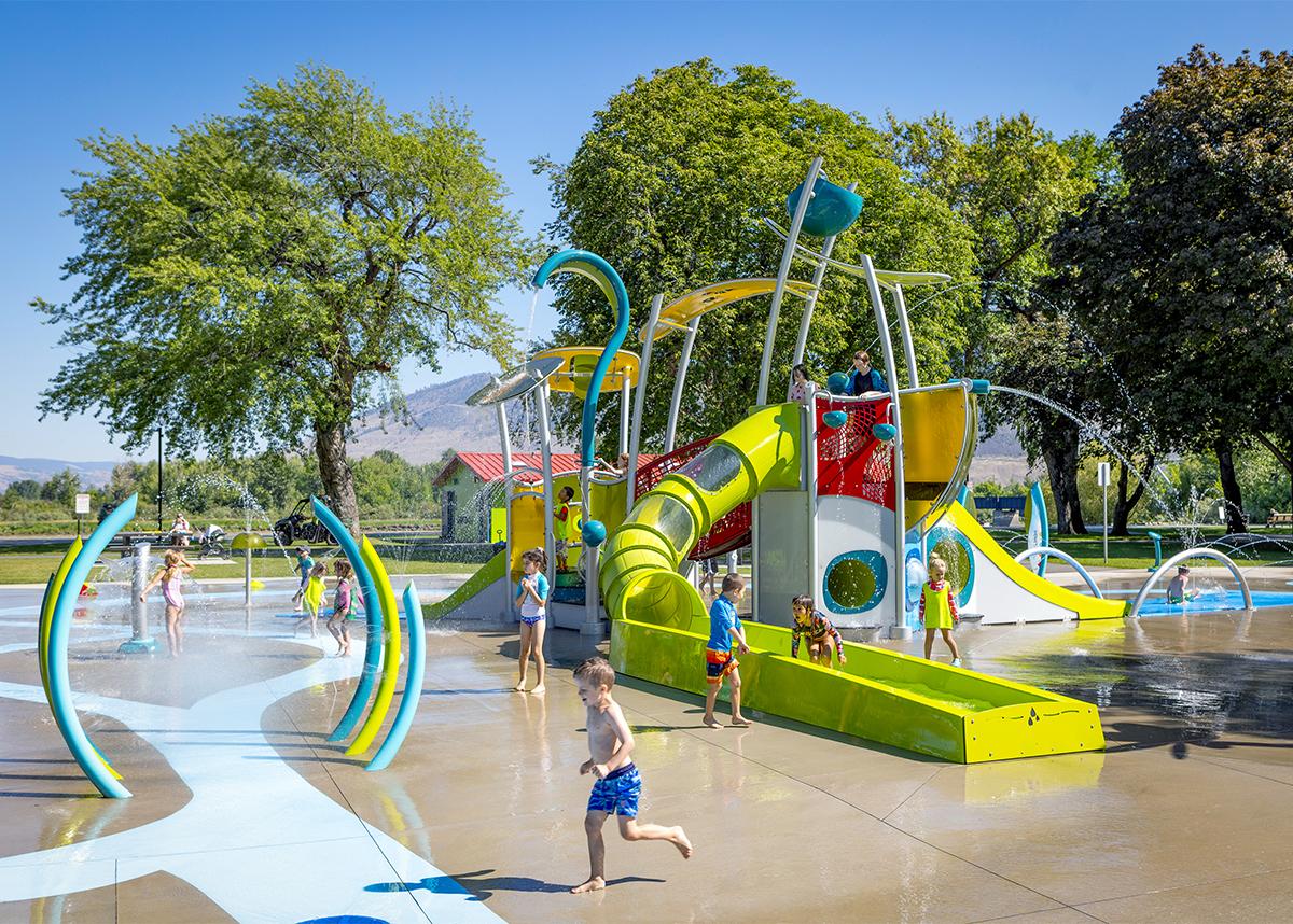 a group of kids playing in a water park with a big water slide