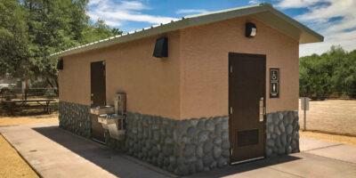 washroom building with Stucco upper walls, river rock lower walls with cedar shake roof and optional water fountain
