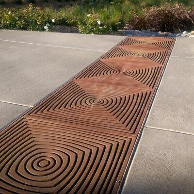 Decorative trench grate crossing a sidewalk