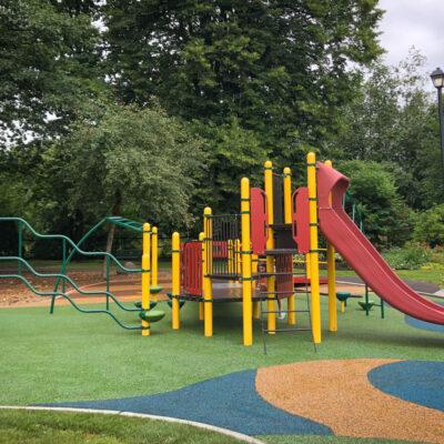 yellow, red & dark green playground on pour in place rubber surfacing (PIP)