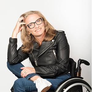 a woman in a black leather jacket sitting in a wheelchair