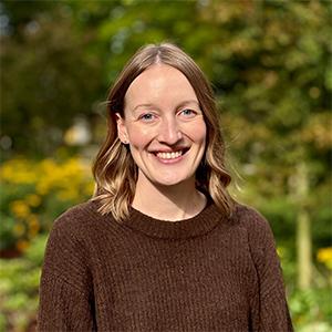 woman in a brown sweater with a nature backdrop