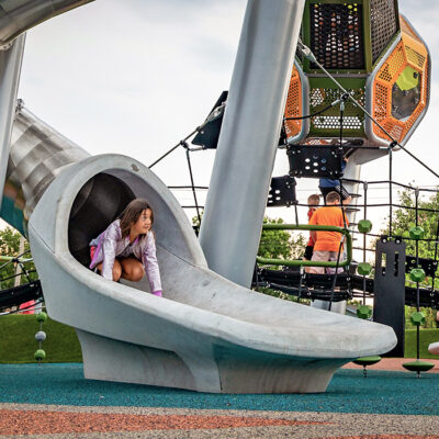 a girl coming out of a slide with a concrete exit