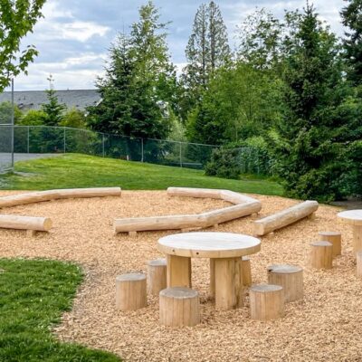 tables, chairs, and benches made of cedar logs creating an outdoor classroom